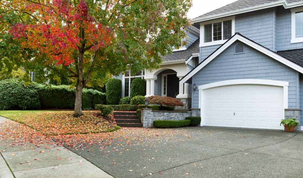 Front view of modern residential home during early autumn season in Northwest of United States. The garage door complements the rest of the house in a pleasing way. Maple trees beginning to change leaf colors.