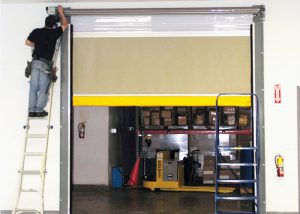 half closed brown garage door with someone working on the coil on a ladder. 