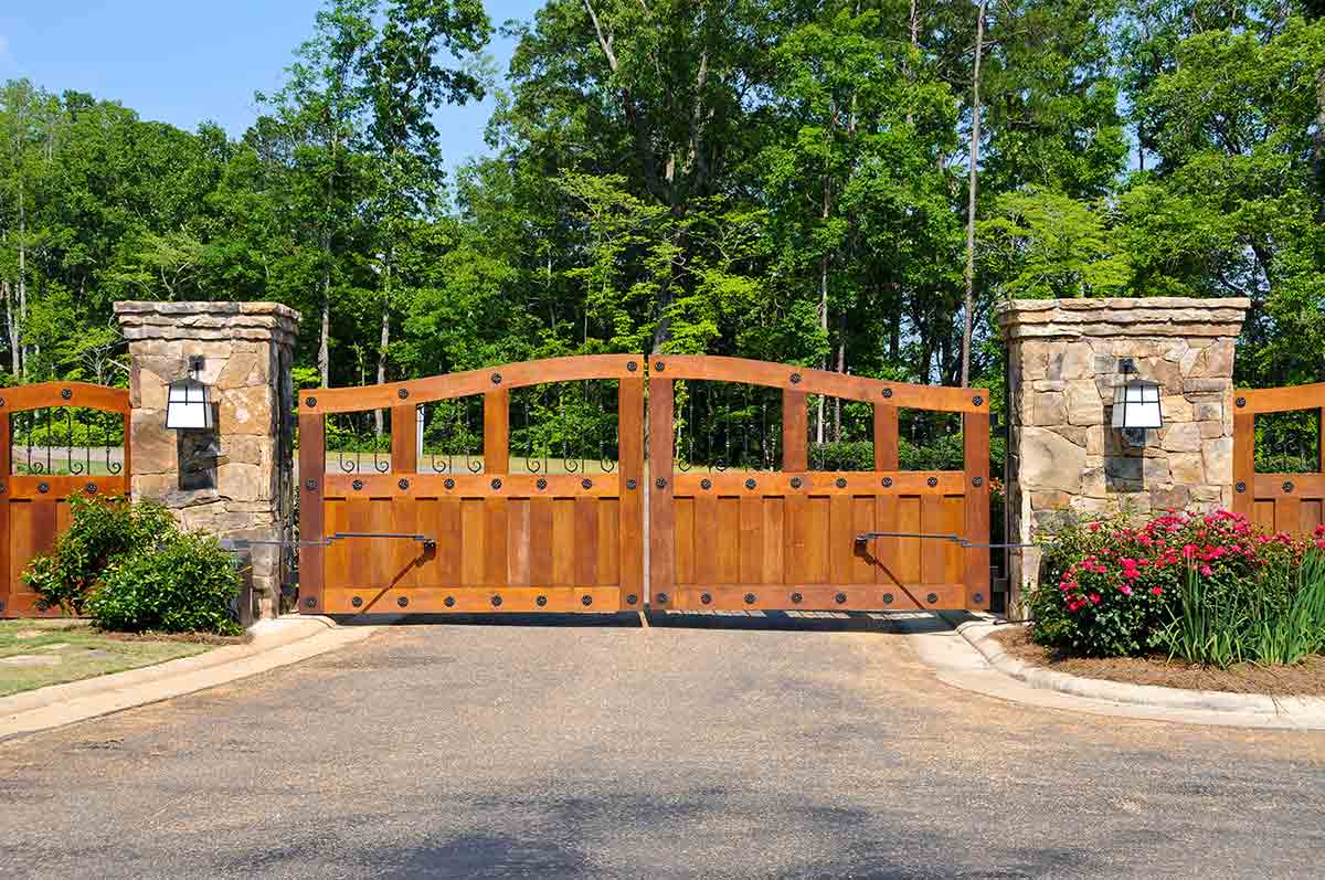 closed wooden driveway gate with tall green trees in the backgorund