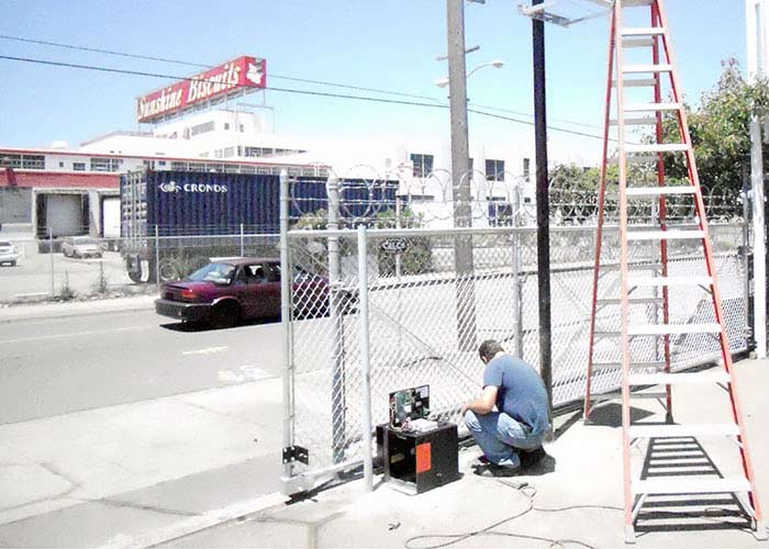 Repairman providing gate repair services by working on an automatic sliding gate