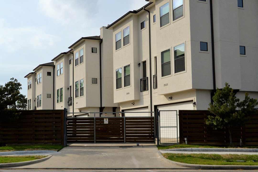 Picture of an apartment complex behind a closed sliding driveway gate.