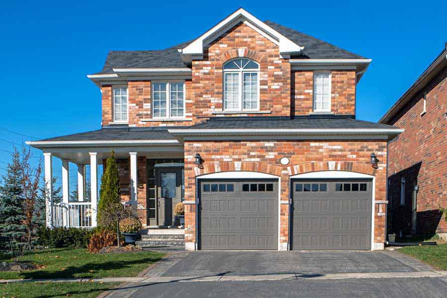 A two-story brick house with an aluminum garage door